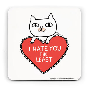 White coaster with an illustration by Gemma Correll of a cat leaning on a frilly heart shaped cusion which reads "I  HATE YOU THE LEAST"