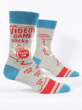 Load image into Gallery viewer, Video Game Men’s crew Socks by Blue Q | £11.95. Ethical and sustainable socks with quirky, humorous designs and vibrant colours. This design features a small man playing videogames on a tv with the words “Video game socks, game on, and on, and on, and on” above.
