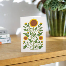Load image into Gallery viewer, Card with sunflower design on a wooden surface with books and a plant in the background