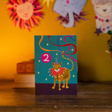 Load image into Gallery viewer, This brightly coloured 2nd birthday card features a tiger and party streamers.  The tiger is wearing a festive ruff around its neck and a striped party hat