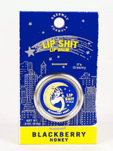 Load image into Gallery viewer, Blackberry & Honey Lip S**t by Blue Q | £7.50. All natural, vitamin E fortified lip balm. The lip balm is contained within a round metal tin with a sticker on the front depicting the moon and a woman hugging with the words “Lip Shit” above.