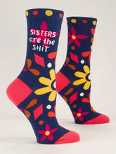 Load image into Gallery viewer, Navy socks with bright floral design in red, pink and yellow.  The text Sisters are the shit is on the side. Red heel and toe.
