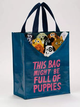 Load image into Gallery viewer, Cute little tote bag by blue Q featuring an illustration by John Bond. The bag is mostly dark petrol blue with bright pink lettering which reads “THIS BAG MIGHT BE FULL OF PUPPIES”. At the top edge of the bag 9 little assorted puppies can be seen, as if they are pulling the rim of the bag down and are inside.
