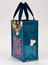 Load image into Gallery viewer, Bag Full of Puppies Lunch Bag Handy Tote by Blue Q | £8.99. Cute little tote bag by blue Q featuring an illustration by John Bond. The bag is mostly dark petrol blue with bright pink lettering which reads “THIS BAG MIGHT BE FULL OF PUPPIES”. At the top edge of the bag 9 little assorted puppies can be seen, as if they are pulling the rim of the bag down and are inside.