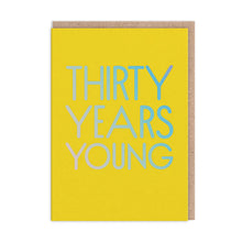 Load image into Gallery viewer, Bright yellow card with large holographic capital letters reading “THIRTY YEARS YOUNG”
