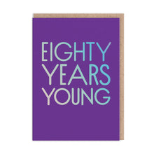 Load image into Gallery viewer, Bright purple card with silver holographic capital lettering “EIGHTY YEARS YOUNG”
