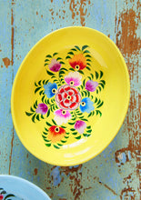 Load image into Gallery viewer, Bright yellow enamel ahallow bowl with floral design on a rustic blue wooden background