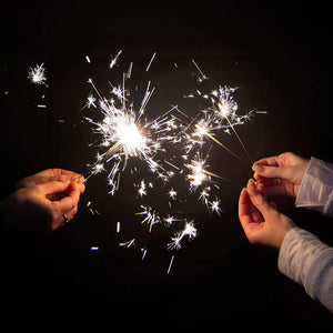 the sparklers are seen in people's hands, holding several at one time.  The sparklers are alight.