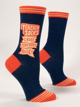 Load image into Gallery viewer, Navy socks with a bright orange top, heel and toe.  The words “Teacher Socks ‘cause Teachers Rock!” On the side of the sock with emphasising design around.
