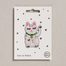 Load image into Gallery viewer, A sweet little waving lucky cat, white with pink ears and a green collar with a gold pendant on it.  There is also three little pink and green flowers on the front of the cat.  The patch is shown on its backing card which has small stars on it.