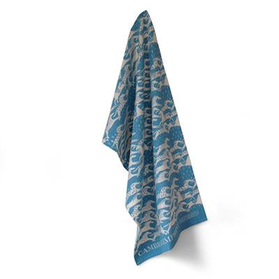 The teatowel is seen hanging.  It has a turquoise blue background with a repeating design of many running white horses all over.  The effect is almost like waves from afar.