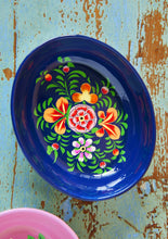 Load image into Gallery viewer, Decorative dark blue shallow enamel oval bowl with bright floral design on a rustic wooden surface
