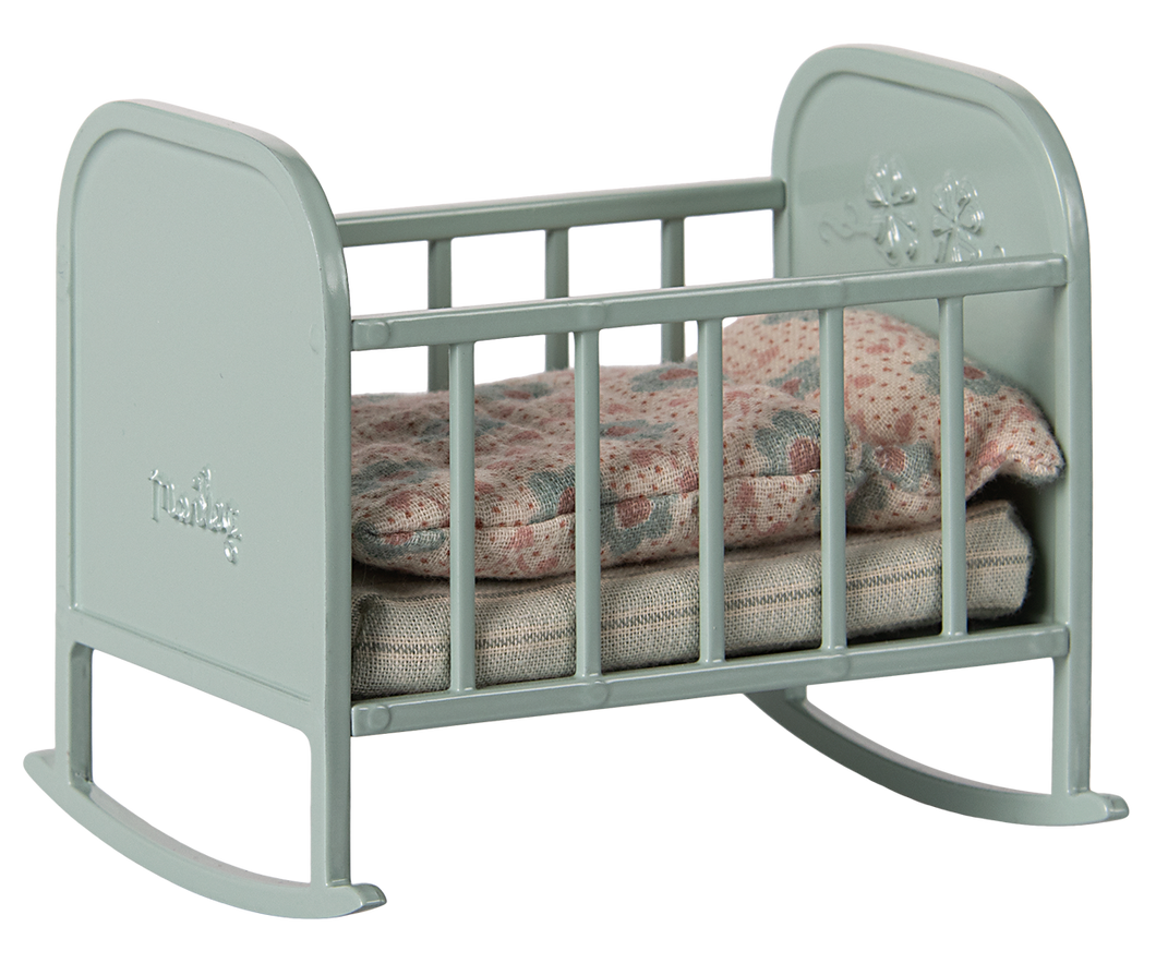 A metal, mint blue cradle with grey stripey matress and floral duvet and pillow in muted colours. 