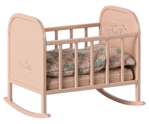 A light pink metal cradle with stripey matress and floral duvet and pillow in muted colours