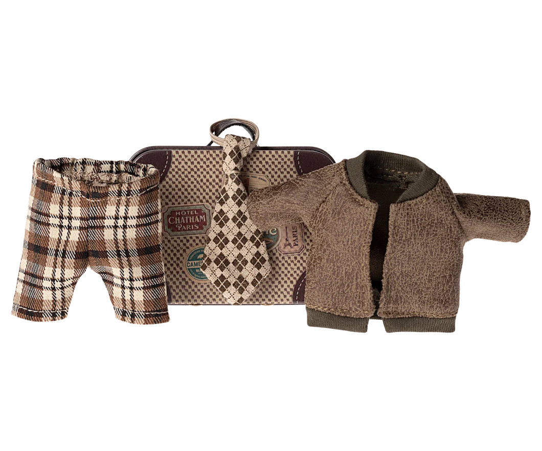 little metal suitcase in the style of a vintage one with destination and hotel stickers. The clotes include a check brown and beige wide tie, Brown tartan check trousers and a brown fleecy jacket.
