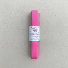 Load image into Gallery viewer, A 5-meter roll of bright pink cotton ribbon, packaged with a white paper label, placed on a textured gray surface.
