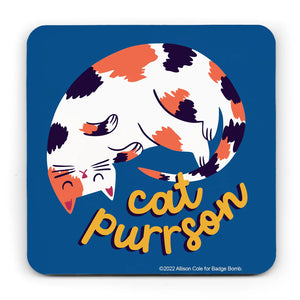 This coaster has a blue background and curved off edges.  It has an illustration of a tortoisehll curled up sleeping cat with the words "cat purrson" underneath