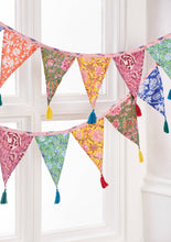 Load image into Gallery viewer, Colourful fabric bunting with tassels hanging against a white window frame.
