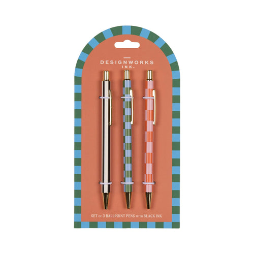 Set of three ballpoint pens with black ink in packaging, featuring 'Designworks Ink' branding. One pen has vertical black and white stripes, the other two have a checked design, one with pink and orange the other with green and blue.