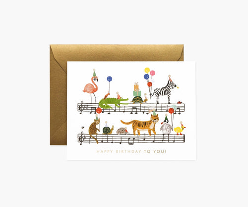 This card has musical staves with the tune of “Happy Birthday To You” with various animals wearing party hats and holding balloons.  The illustration has gold foil details and the wording at the bottom of the card “HAPPY BIRTHDAY TO YOU!” is in gold.  The card is cream and the enviope is metallic gold.