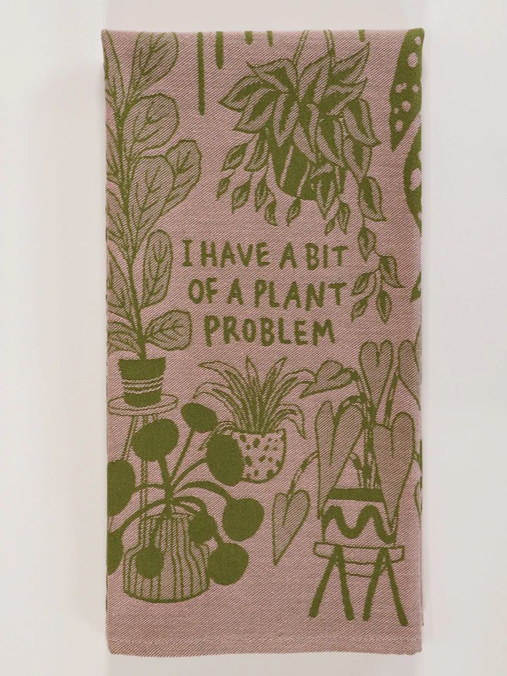 tea towel with a light pink background with green plants and writing in the center that reads 