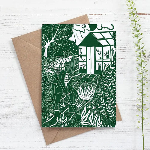 Blank inside greetings card featuring a woman digging in her garden with a cat and greenhouse in the background.  The artwork is taken from an original linocut by Nicole Revy of Prints by the Bay.