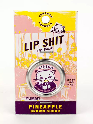 Pineapple Brown Sugar Lip S**t by Blue Q | £7.50. All natural, vitamin E fortified lip balm. The lip balm is contained within a round metal tin with a sticker on the front depicting a white cat licking an ice cream with the words “Lip Shit” above. 