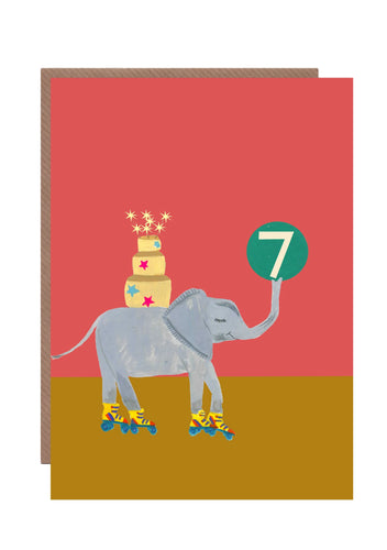 This 7th birthday card by Hutch Cassidy features an elephant on roller skates with a large tired birthday cake on its back and a large green hall with the number 7 is carried aloft by its trunk.
