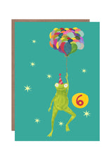 Load image into Gallery viewer, This 6th birthday card by Hutch Cassidy featured a smiling frog in a striped party hat being held aloft by a large bunch of multicoloured balloons he is holding.  The background is bright turquoise and the number 6 is prominently seen in a large yellow circle 
