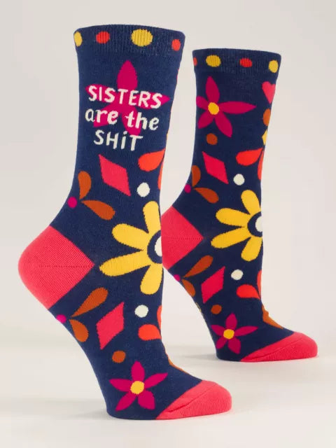 Navy socks with bright floral design in red, pink and yellow.  The text Sisters are the shit is on the side. Red heel and toe.