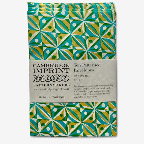 ten patterned envelopes with a paper belly band with the Cambridge Imprint Logo and product information.  The pattern is a block print of repeating squares with dots and triangles within them in turquoise and yellow