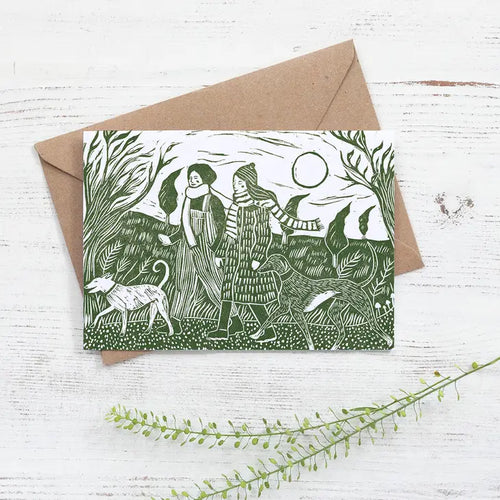 greetings card from a linocut by Nicola Revy, featuring two women in hats and scarves walking dogs