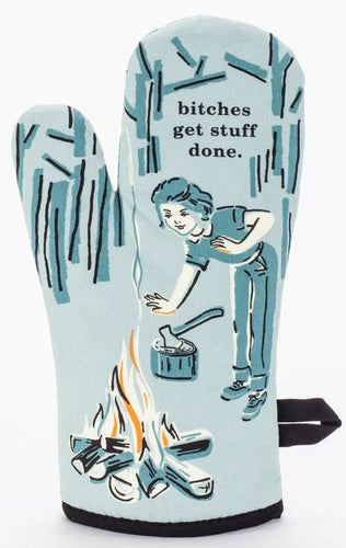 blue oven glove with illustration of a woman cooking on a campfire.  In the background is a woodcutting axe and tress.  Above her a re the words 