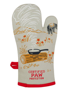 The reverse of the oven mitt has the words “CertifiedPaw Protection” at the bottom and an illustration of a steaming pan on a log and ahorse grazing in the background