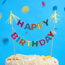 Load image into Gallery viewer, The sweet little &quot;HAPPY BIRTHDAY&quot; bunting with brightly coloured letters and little tassels at either end, is seen on top a cake
