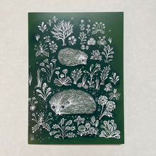 Load image into Gallery viewer, Dark green greetings card with white illustrations of two hedgehogs walking amongst the flowers and plants 
