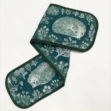 Load image into Gallery viewer, Double oven gloves in deep green with white illustrations of handrawn hedgehogs, trees and flowers.
