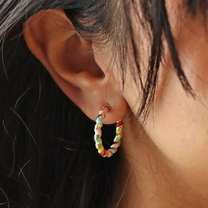 Rainbow Enamel Twist Hoop Earrings in Gold by Lisa Angel | £20.00. A pair of gold hoop earrings with rainbow enamel twists, designed by Lisa Angel. The hoops feature vibrant colours in a twisted pattern, adding a playful and colourful touch to any outfit.