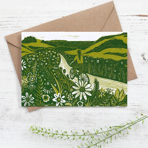 Greetings card of a girl riding a bicycle through a summer country lane.  Green ink.  Taken from linocut by Nicola Revy of Prints by the Bay.