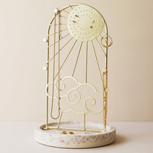 Load image into Gallery viewer, Sunshine Jewellery Stand by Lisa Angel | £22.00. The arched frame is made of gold metal and features a beaming sun design complete with cloud detailing. On the round sun face are holes for studs and hook earrings, while the edge of the frame has pegs made for your necklaces and longer pieces. The base of this stand is made of terrazzo resin in speckled whites, creams and greys to finish this sweet jewellery storage piece. 
