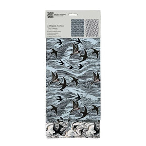 one tea towel has a light blue background while the other has a white background.  Bothe have an over all pattern of the sea and swallows in black