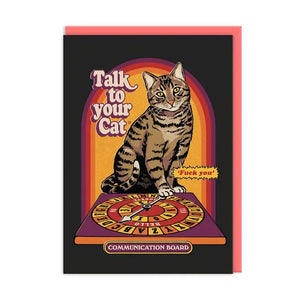 1970s like illustration of a tabby cat sitting neact to a ouija board.  To the left in typically 70's bubble lettering it says "Talk to Your Cat".  A small jaggeddy speech bubble is coming from the cat on smaller writing which reads "Fuck You!"