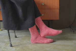 A close up of someone's feet wearing boot socks in a red and white flecked colourway