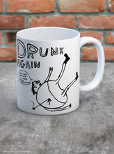 Load image into Gallery viewer, David Shrigley Boxed Mug - Drunk Again | £10.00. White ceramic mug with artwork by David Shrigley.  The words &quot;drunk again&quot; appear above a line drawing of a rotund figure with skinny legs lying on the ground with their legs up in the air.  The figure has an arrow sticking into his back.  A speech bubble reads &quot;I&#39;m not drunk.  I have been Harpooned&quot;
